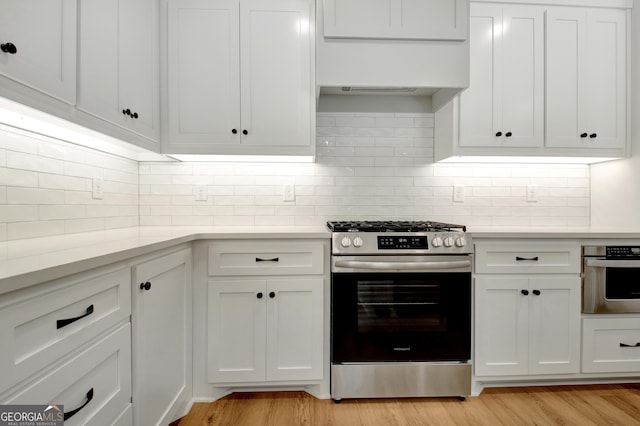 kitchen with white cabinetry, stainless steel appliances, light hardwood / wood-style flooring, and tasteful backsplash