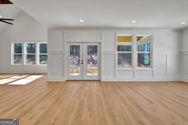 unfurnished living room featuring light wood-type flooring, french doors, vaulted ceiling, and ceiling fan