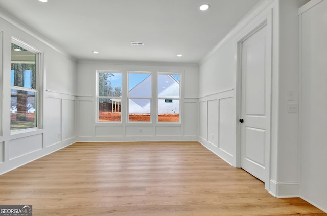 empty room featuring light wood-type flooring and ornamental molding