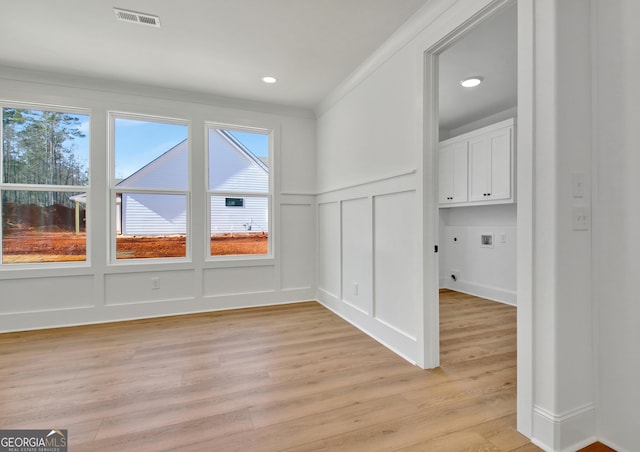 interior space featuring light wood-type flooring, a wealth of natural light, and ornamental molding