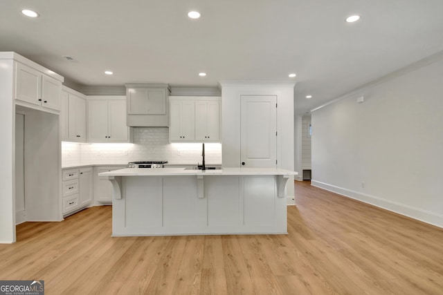 kitchen featuring white cabinetry, light hardwood / wood-style floors, and a kitchen island with sink