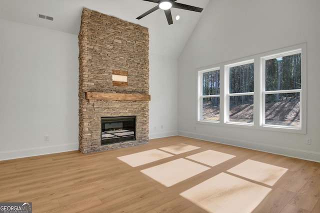 unfurnished living room featuring ceiling fan, light hardwood / wood-style floors, a stone fireplace, and high vaulted ceiling