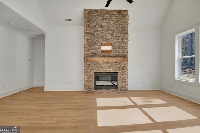 unfurnished living room with a wealth of natural light, hardwood / wood-style floors, and a stone fireplace