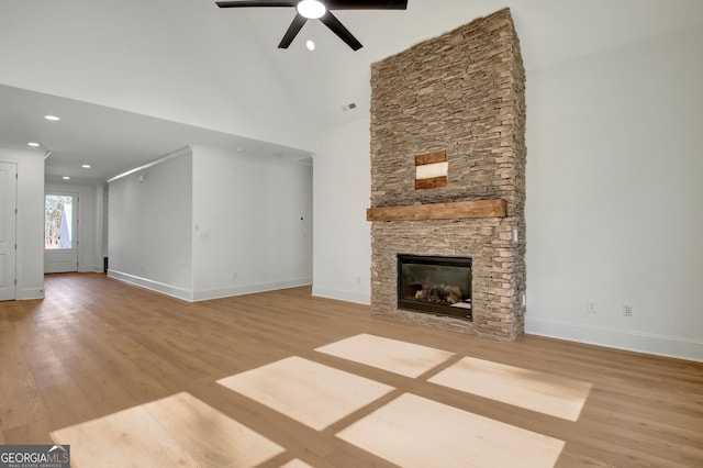 unfurnished living room with ceiling fan, light hardwood / wood-style flooring, a stone fireplace, and high vaulted ceiling