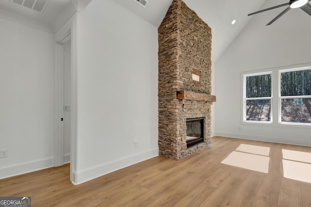 unfurnished living room with ceiling fan, light wood-type flooring, high vaulted ceiling, and a fireplace