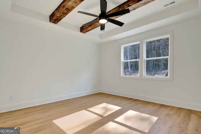 empty room with beam ceiling, ceiling fan, a raised ceiling, and light hardwood / wood-style flooring