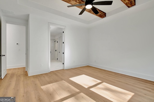 unfurnished bedroom with light wood-type flooring, ceiling fan, and a tray ceiling