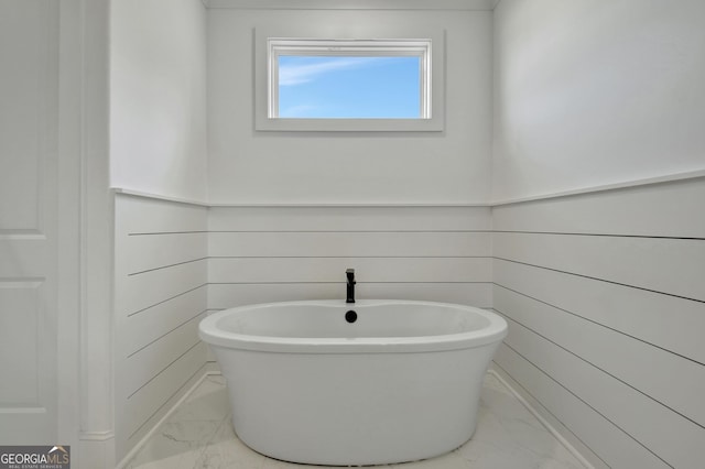 bathroom featuring a bathtub and wooden walls