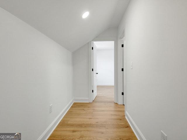 corridor featuring light wood-type flooring and vaulted ceiling