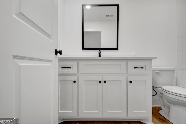 bathroom with toilet, hardwood / wood-style floors, and vanity