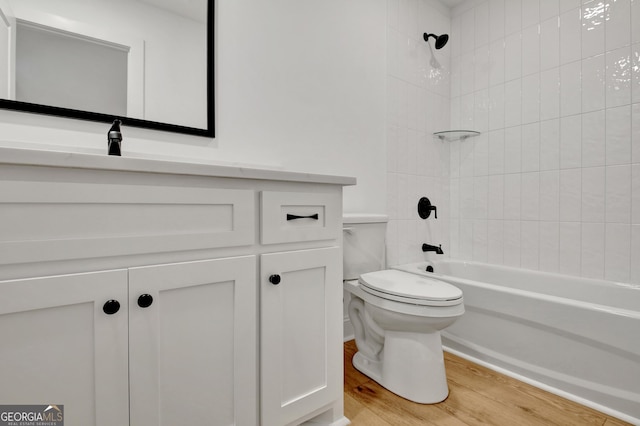 full bathroom with toilet, tiled shower / bath combo, vanity, and hardwood / wood-style floors