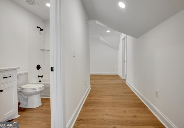 bathroom featuring toilet, wood-type flooring, and shower / bathing tub combination