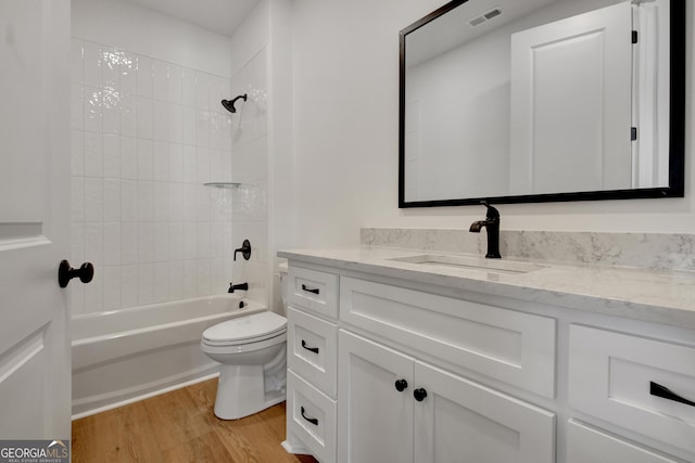 full bathroom with hardwood / wood-style flooring, toilet, vanity, and tiled shower / bath