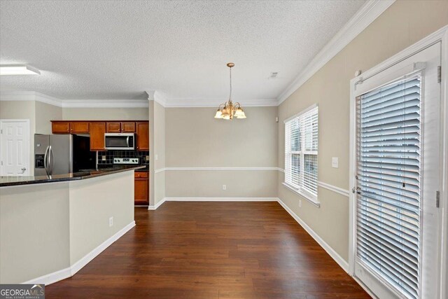 kitchen with stainless steel appliances, a notable chandelier, a textured ceiling, ornamental molding, and pendant lighting