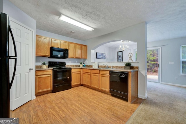 kitchen with an inviting chandelier, black appliances, sink, light hardwood / wood-style flooring, and a textured ceiling