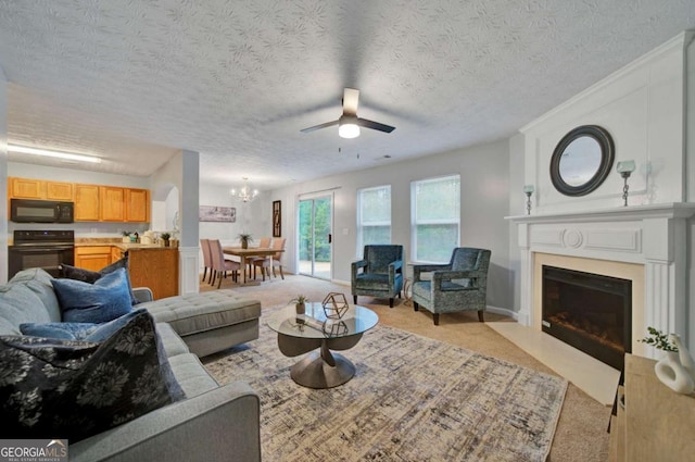 carpeted living room with a textured ceiling and ceiling fan with notable chandelier