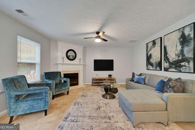 carpeted living room featuring ceiling fan and a textured ceiling