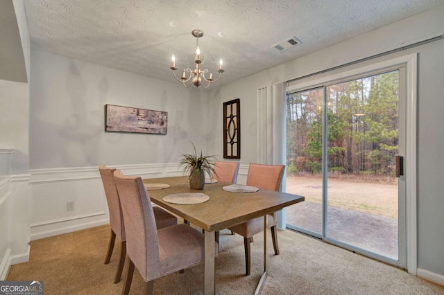 carpeted dining space with a chandelier and a textured ceiling