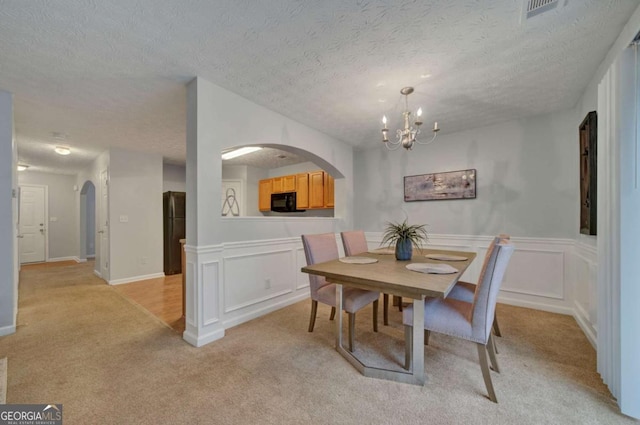 carpeted dining space featuring a textured ceiling and an inviting chandelier