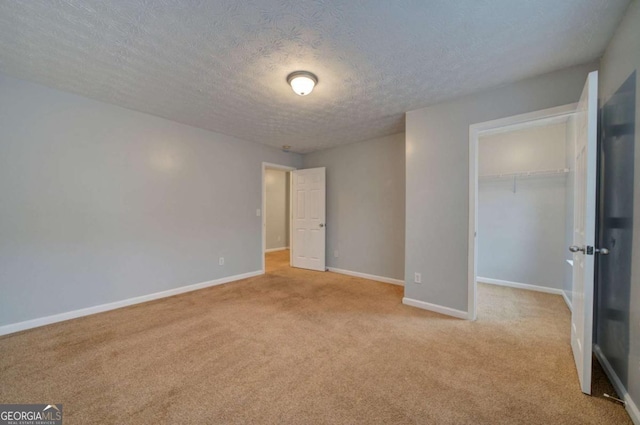 unfurnished bedroom with light colored carpet, a textured ceiling, and a closet