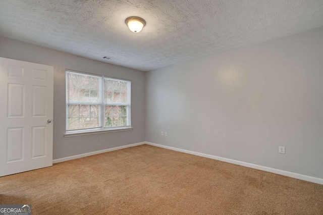 unfurnished room featuring a textured ceiling and light carpet