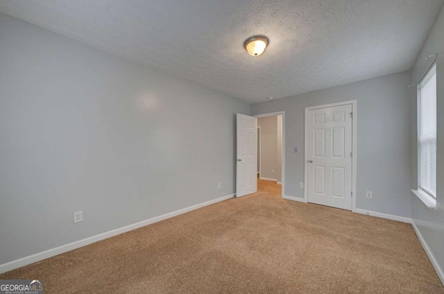 unfurnished bedroom with a textured ceiling and light colored carpet