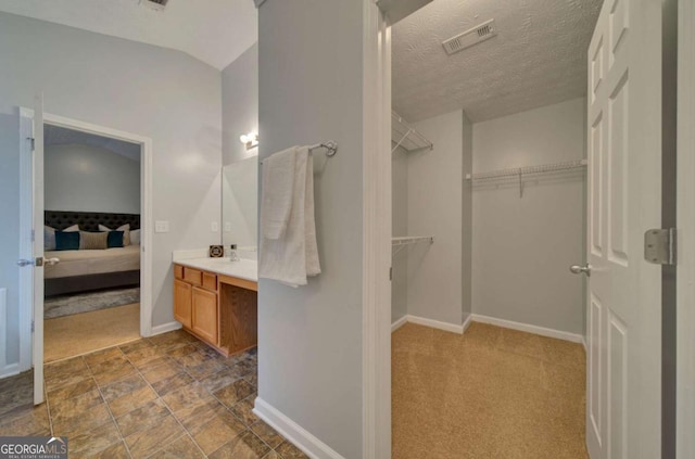 bathroom featuring vaulted ceiling, vanity, and a textured ceiling