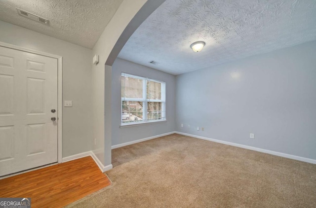 entryway with light carpet and a textured ceiling