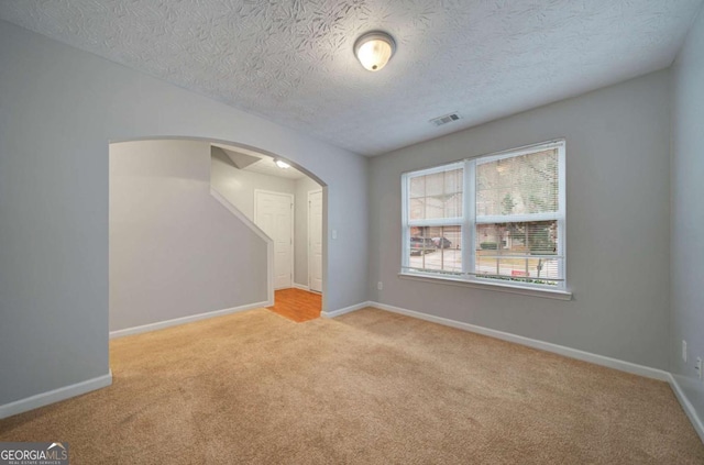 empty room featuring a textured ceiling and light colored carpet