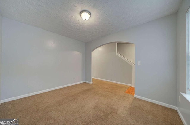 spare room featuring light carpet and a textured ceiling