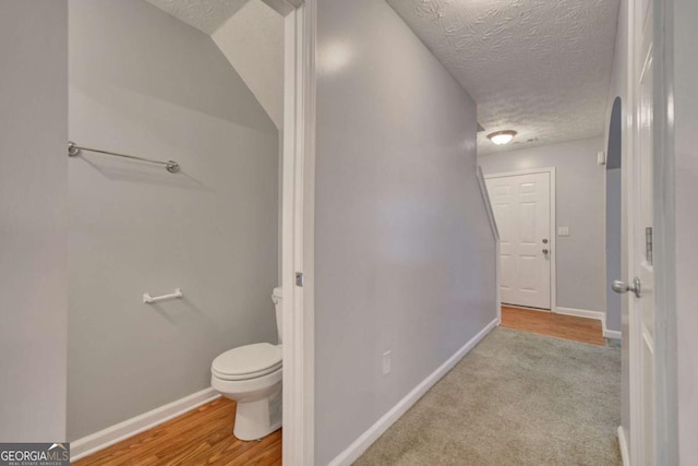 bathroom featuring wood-type flooring, a textured ceiling, and toilet