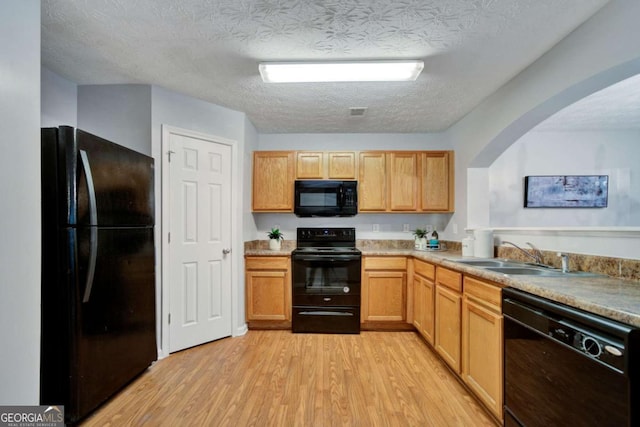 kitchen featuring black appliances, sink, a textured ceiling, light brown cabinetry, and light hardwood / wood-style floors