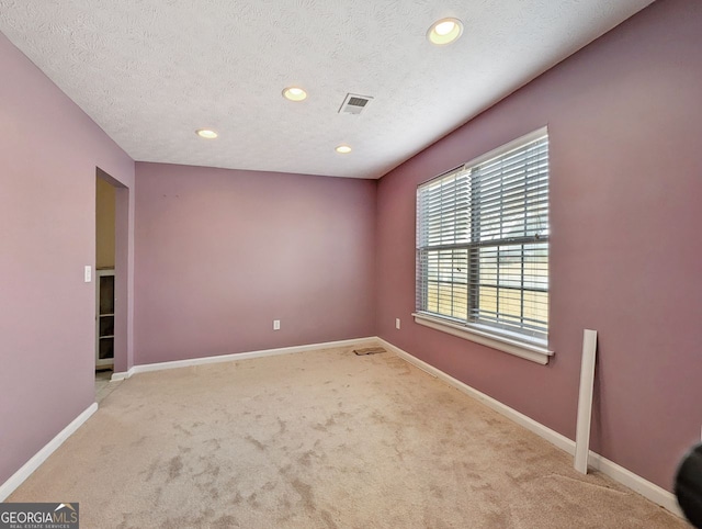 carpeted spare room with a textured ceiling