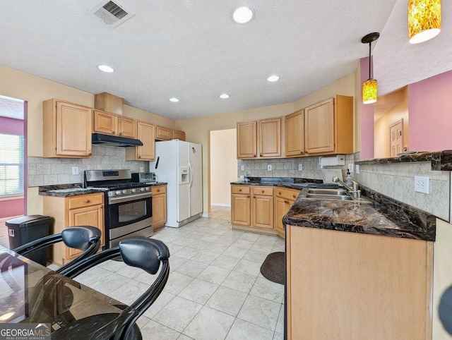 kitchen with white fridge with ice dispenser, gas stove, pendant lighting, light brown cabinets, and sink