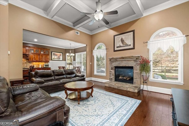 living room with a stone fireplace, ceiling fan with notable chandelier, dark hardwood / wood-style floors, and coffered ceiling