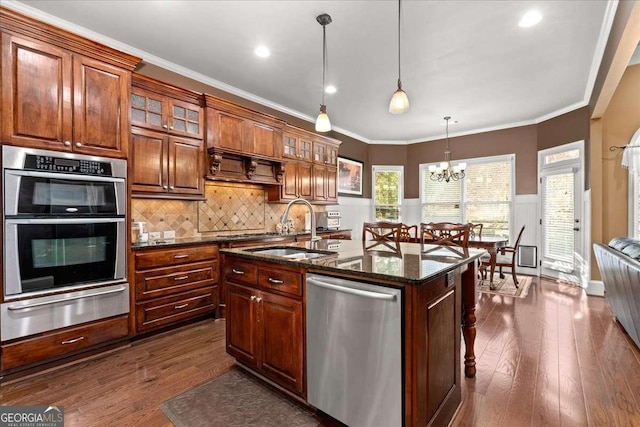 kitchen with hanging light fixtures, sink, an island with sink, appliances with stainless steel finishes, and a chandelier