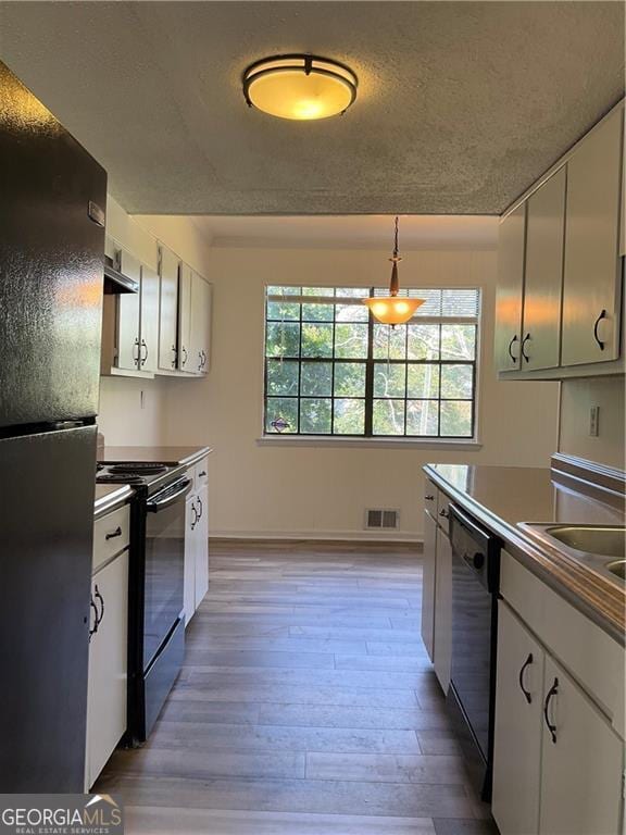 kitchen with wood-type flooring, sink, white cabinets, hanging light fixtures, and black appliances