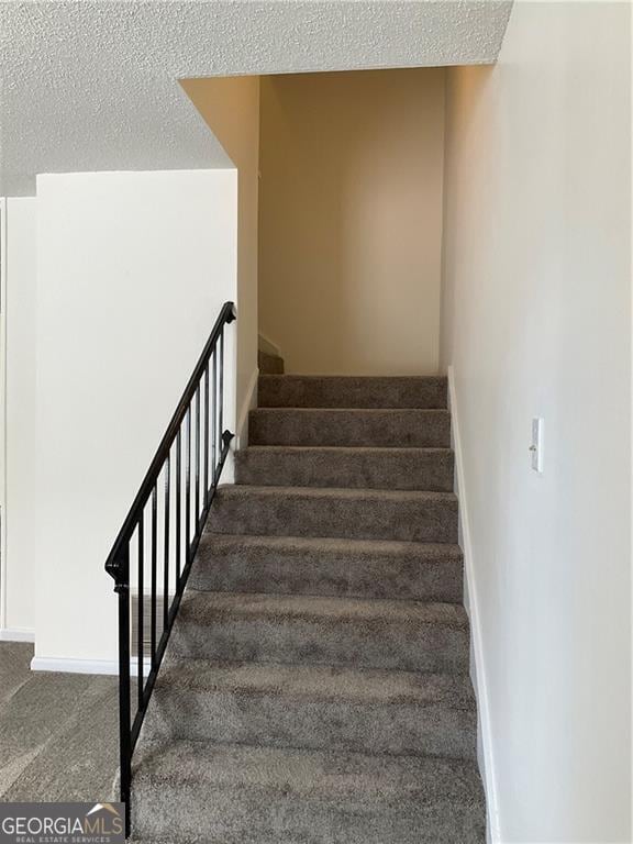 staircase with carpet floors and a textured ceiling