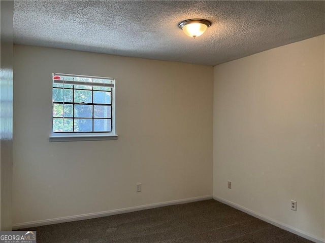 empty room with a textured ceiling and dark carpet