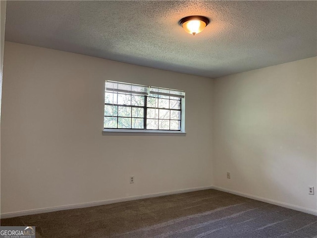 empty room with dark carpet and a textured ceiling