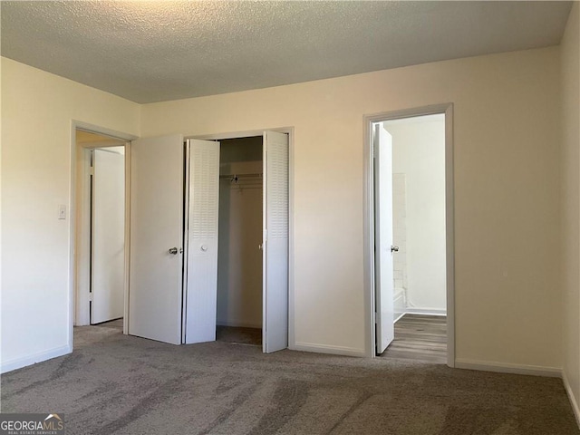 unfurnished bedroom featuring dark carpet, a textured ceiling, and a closet