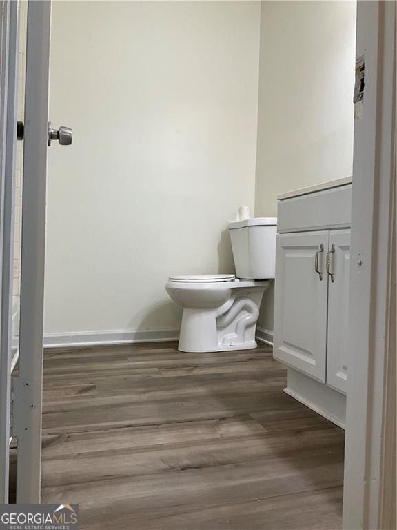 bathroom with wood-type flooring, toilet, and vanity