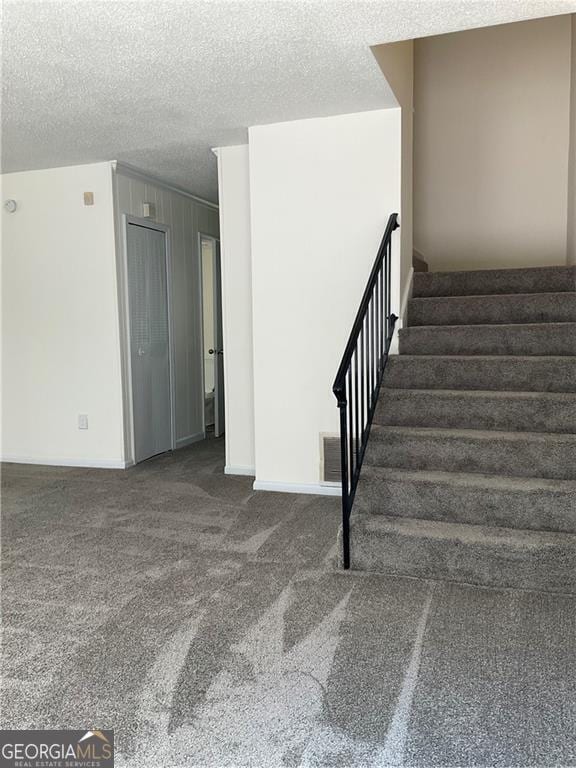 staircase featuring a textured ceiling and carpet