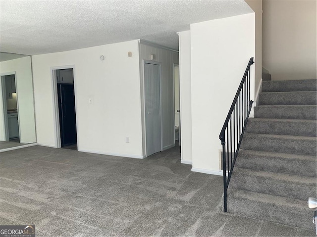 interior space with a textured ceiling and carpet flooring