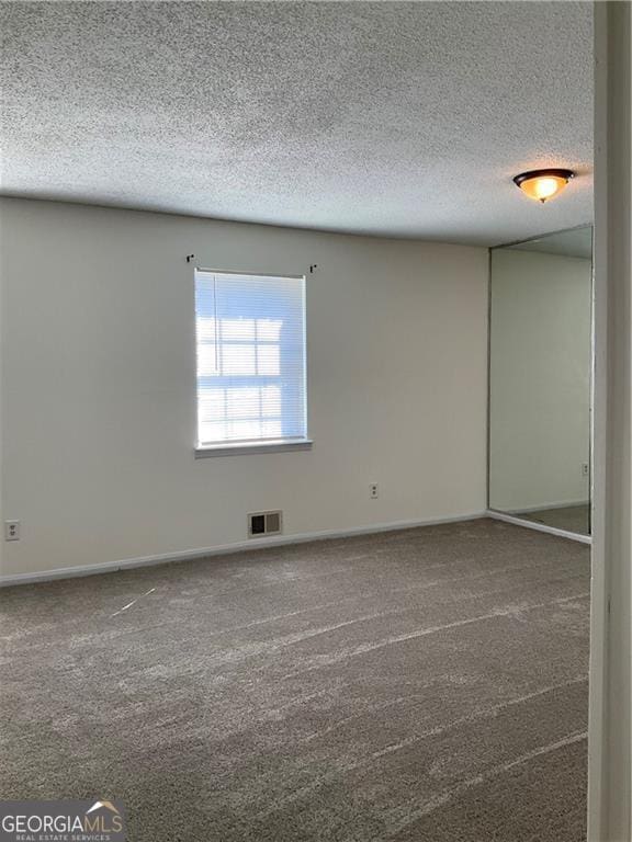 empty room featuring carpet floors and a textured ceiling