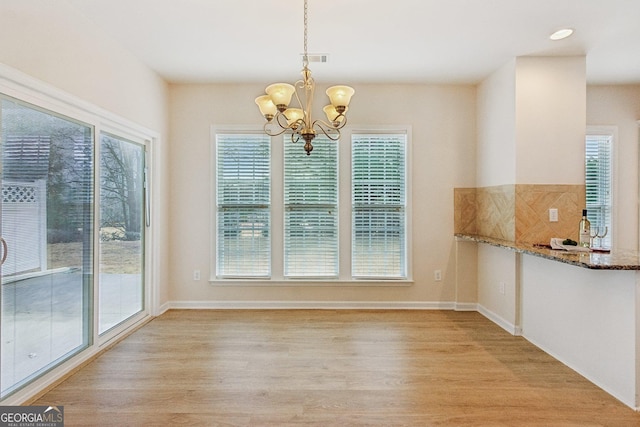 unfurnished dining area featuring a chandelier and light wood-type flooring