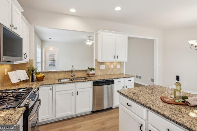 kitchen with appliances with stainless steel finishes, white cabinetry, stone countertops, and sink