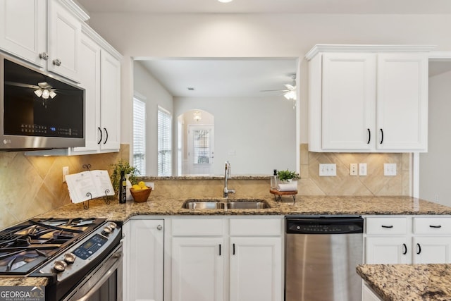 kitchen featuring stainless steel appliances, stone countertops, white cabinetry, and sink