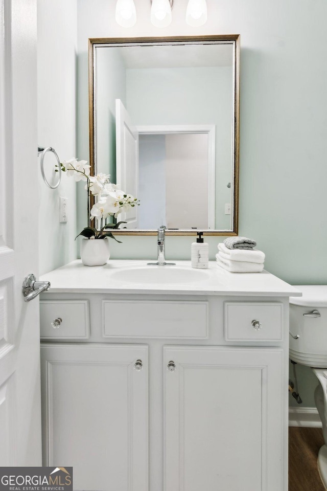 bathroom with hardwood / wood-style flooring, vanity, and toilet