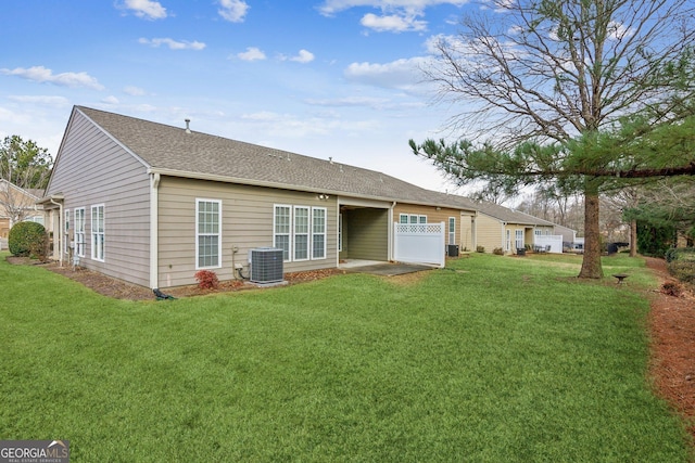 rear view of house featuring central air condition unit and a lawn